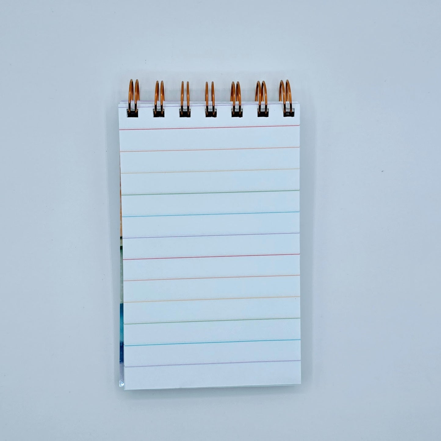 Rainbow-lined pages inside mini notebook with copper wire binding and premium white paper