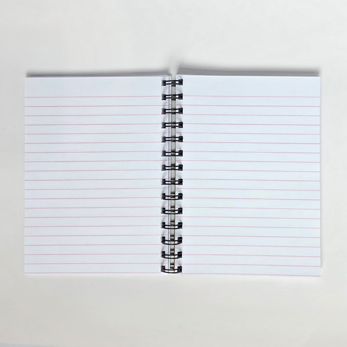Pink-lined pages inside 5x7 notebook with spiral binding and smooth white paper