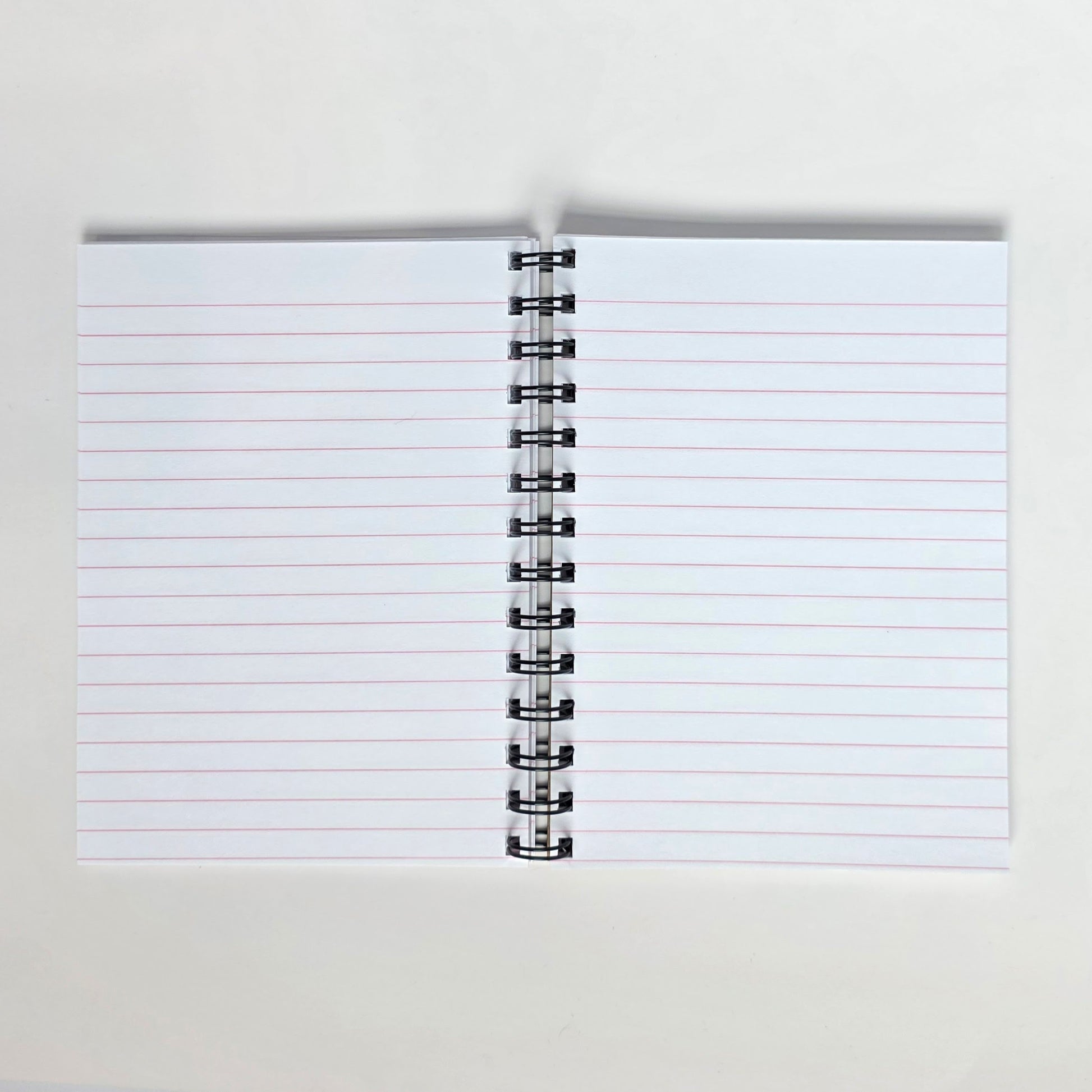 Pink-lined pages inside 5x7 notebook with spiral binding and smooth white paper
