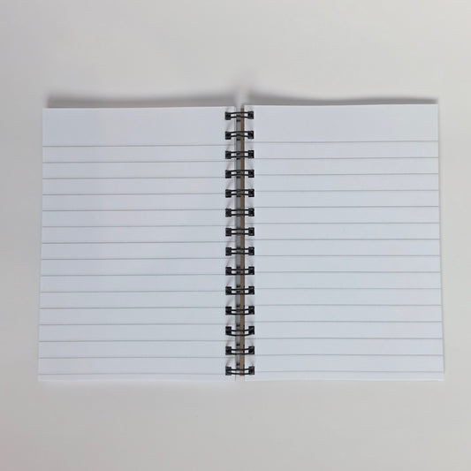White-lined pages inside a spiral-bound 5x7 notebook with silver wire and smooth paper
