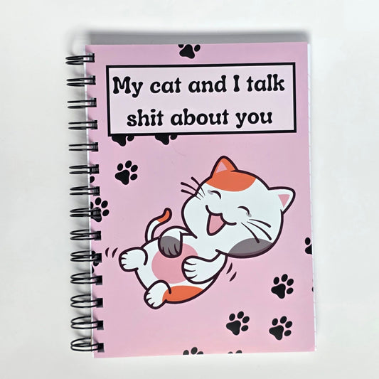 Funny pink cat notebook with the phrase “My cat and I talk sht about you” and cartoon cat laughing on cover