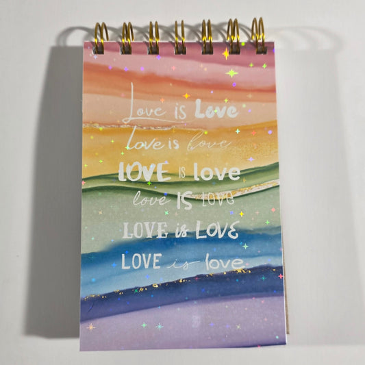 Holographic rainbow pocket notebook with “Love is Love” text and gold wire binding