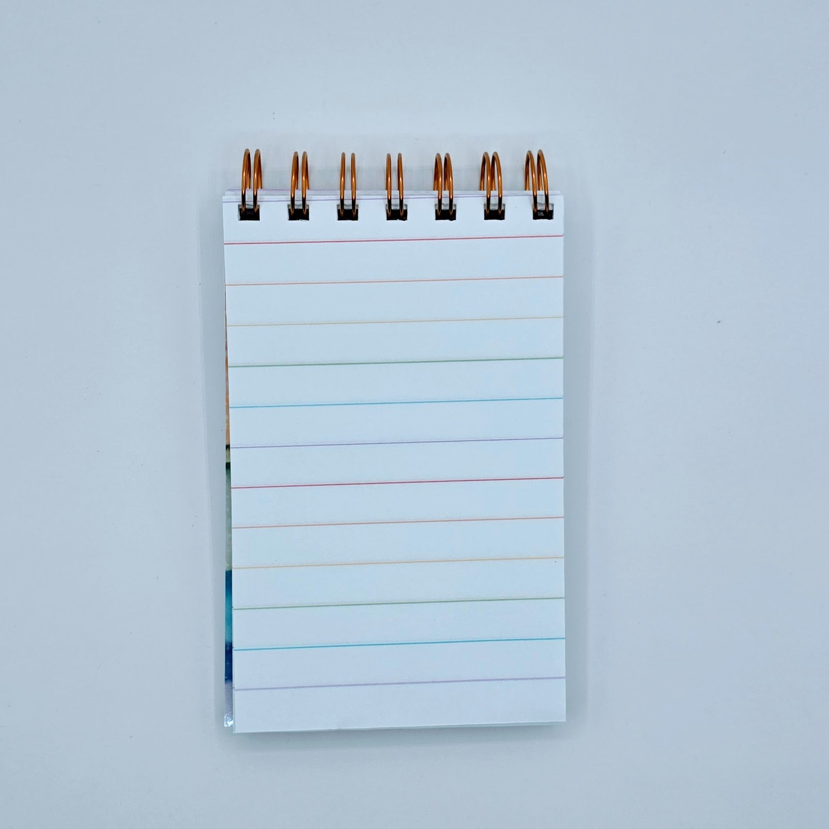 Rainbow-lined pages inside mini notebook with copper wire binding and premium white paper