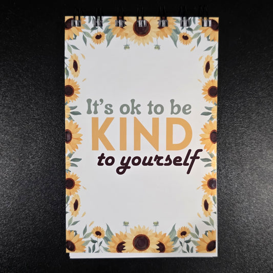 Notebook with sunflower design and motivational quote on a dark background